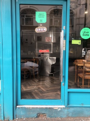 Glass door with blue frame. Push handle on right to open.