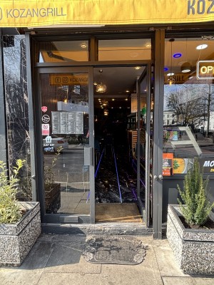 Glass doors with black frame ahead. Push doors to open from center. Planters on both sides of doors.