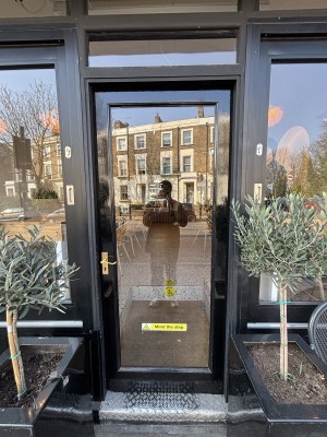 Glass door with black frames. Push gold handle on left to open.