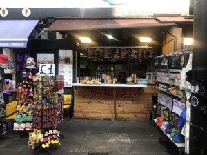 From pavement facing venue. Product shelves on left and right. Counter at back.