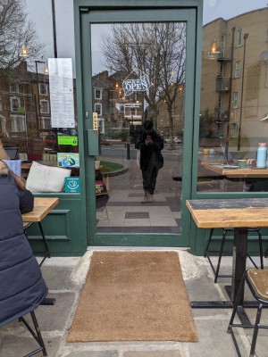 Short ramp up to glass door with green frame and metal handle on left. Push to open.