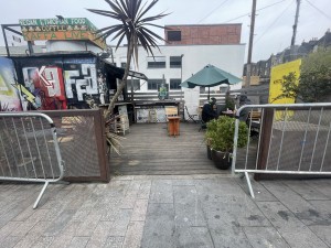 From street facing venue. Opening ahead. Metal barriers on both sides.
