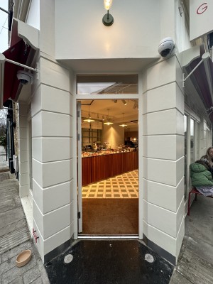 Glass door with white frame. Push from right to open.