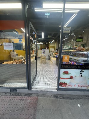 Glass door with black frame ahead. Push black metal handle on right to open.