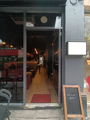Glass door with grey metal frame. Push from left to open.