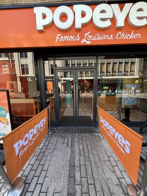 From pavement facing venue. Restaurant barriers on left and right. Path in centre to doors at the back.