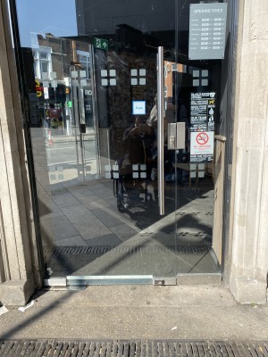Glass door with metal frame ahead. Pull from metal handle on right to open.