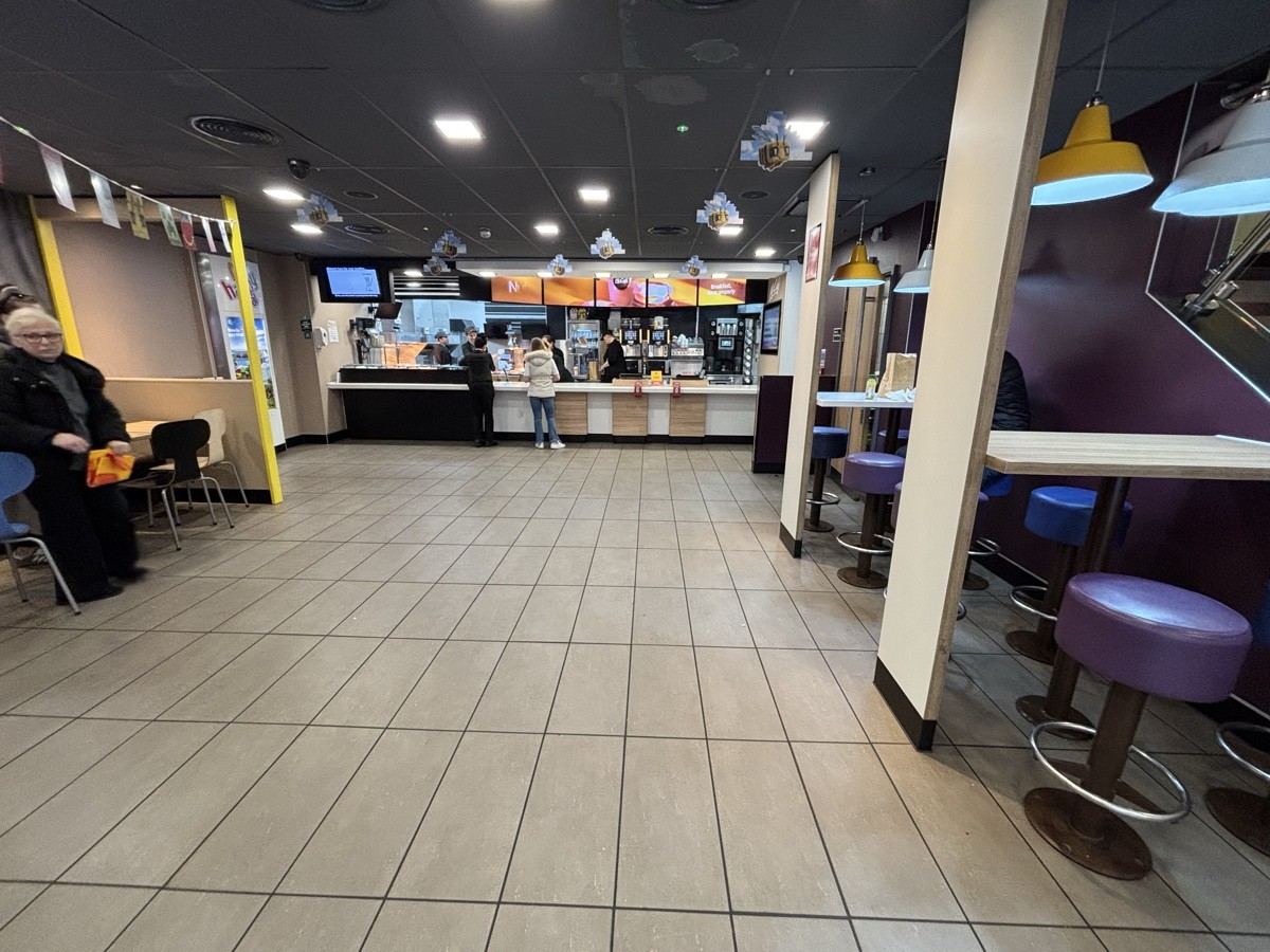 From after bins facing straight. High tables and stools on right. Counter at the back.