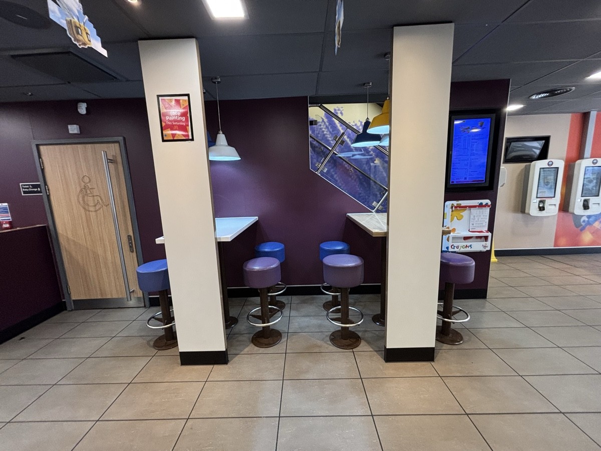 From after self ordering screen facing right. High tables and stools at the back. Toilet on back left.