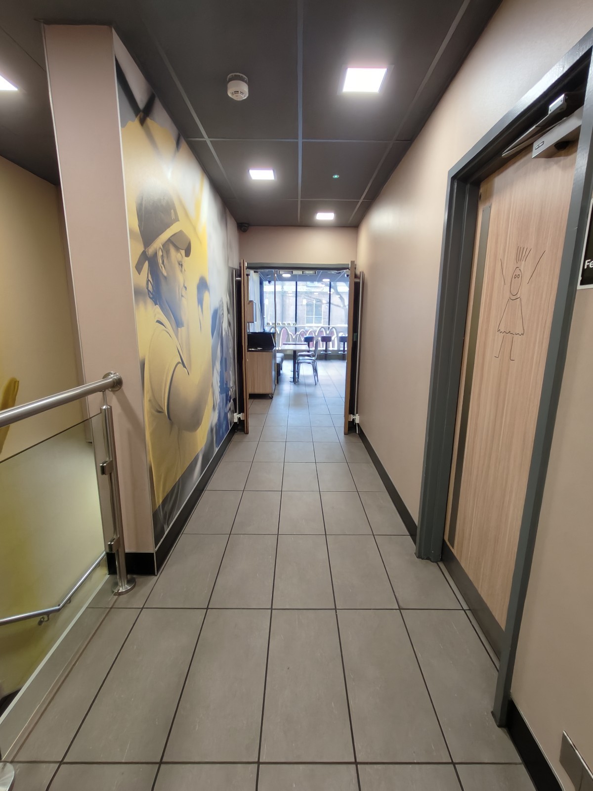 From non-accessible toilets facing left. Path ahead to doors at back.