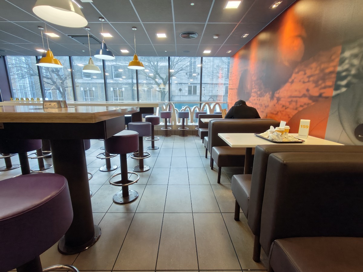 From end of half booths on right facing left. Booths along right. Path ahead to stools and high table at back and on left.