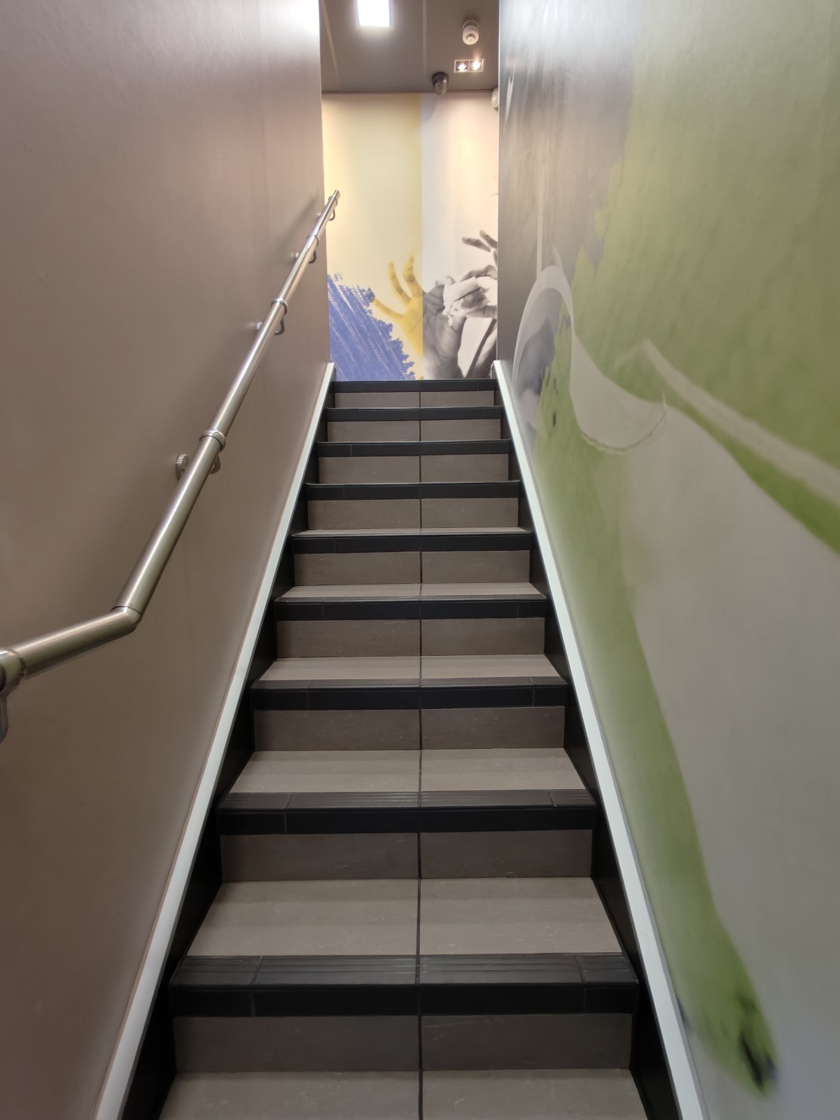 From landing facing straight. Stairs continue going up. Handrail along left.