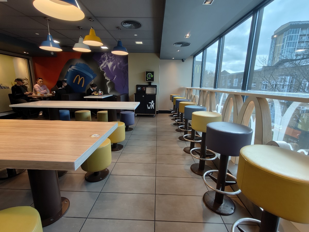 From end of booths facing left. High table and stools on right. Table and stools on left. Booths behind at back left.