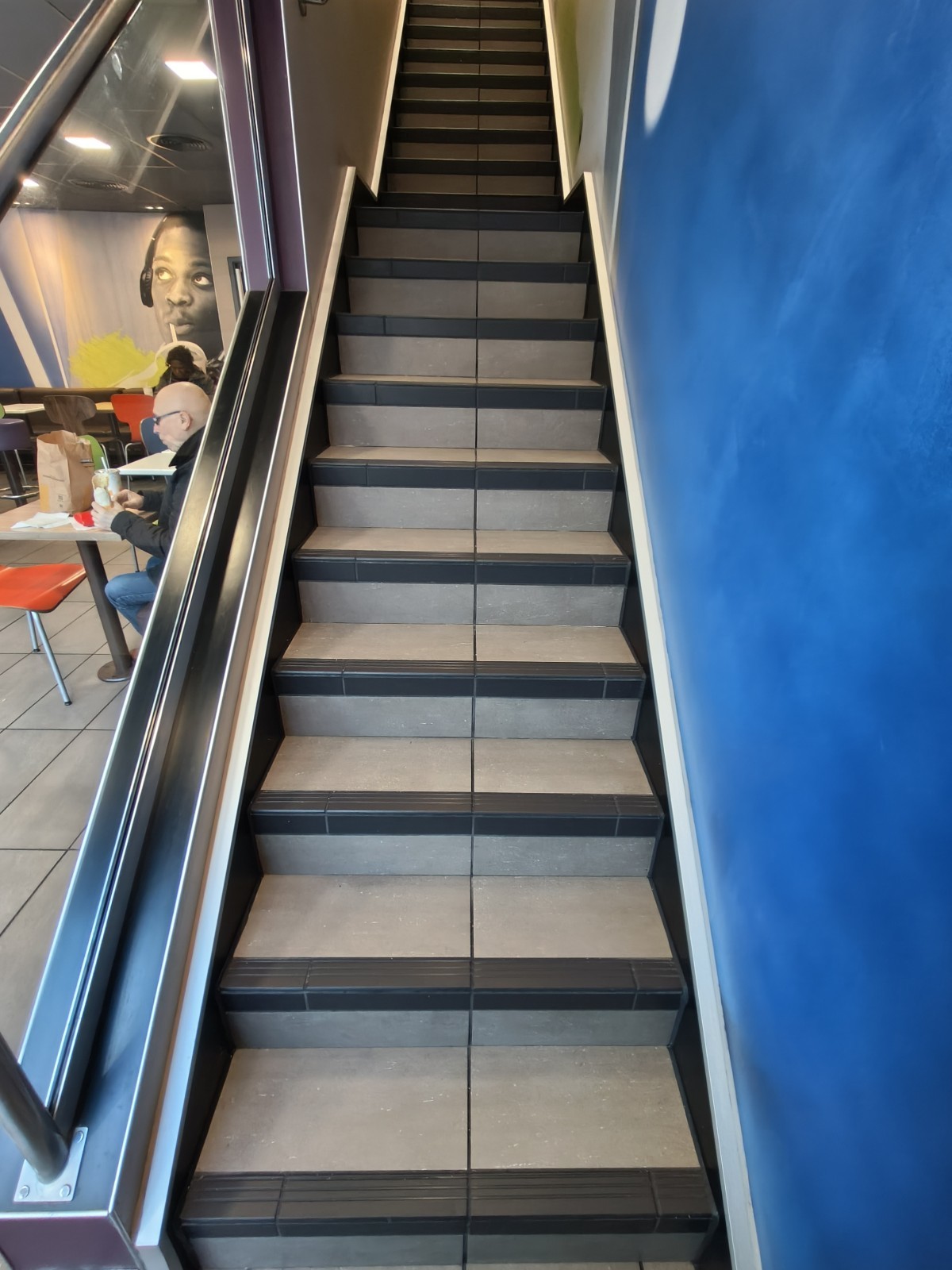 From end of path facing left. Stairs going up to landing at back. Silver handrail on left.