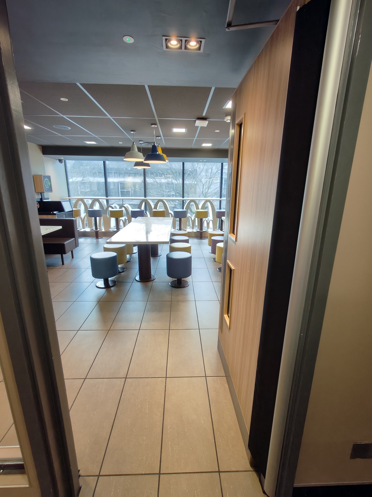 From after preceding door facing left. Second wooden door with glass panel ahead. Push from left to open.