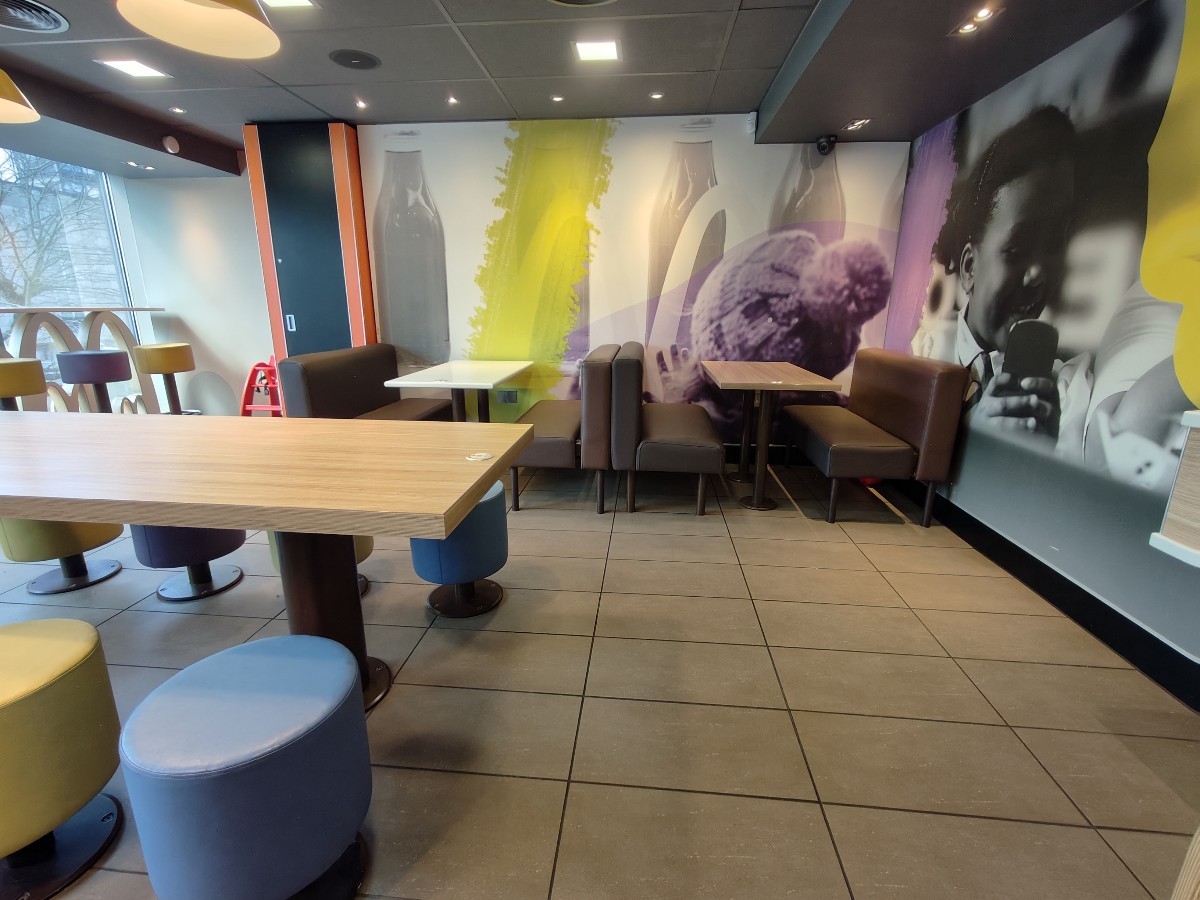 From door facing right. Table and stools on left. Path ahead to booths along back.