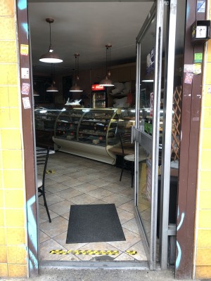 Glass door with grey frame. Push handle on left to open.