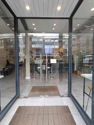 Glass doors with silver handles in middle. Push to open.