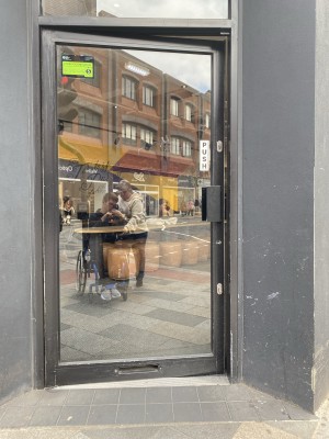 Glass door with green frame ahead. Push from handle on right to open.
