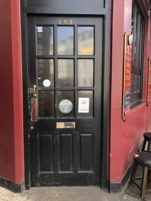 Black door with glass panel. Push from left to open.