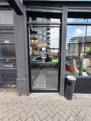Black framed glass door. Push black handle on right to open.