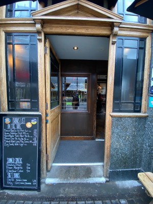 Glass door, with wooden doorframe. Push on right to open.