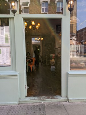 Glad door with green frame and metal handle on left. Push to open.