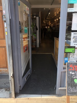 Glass door with grey frame. Push handle on right to open.