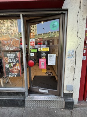 Glass door with grey frames. Push from red handle on left to open.