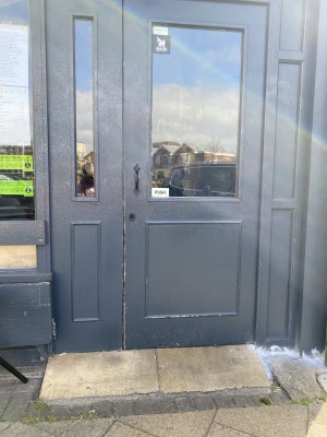 Wooden door with glass panel ahead. Push from metal handle on left to open