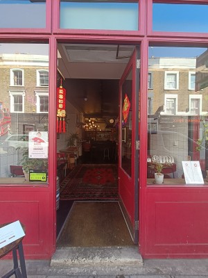 Glass door with red, wooden frame. Push from left to open.