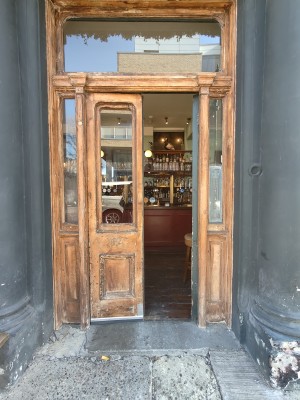 From in between outdoor front picnic benches facing left. Wooden framed glass doors. Push from centre to open.