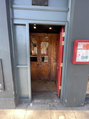 Red wooden door ahead. Push from left to open.