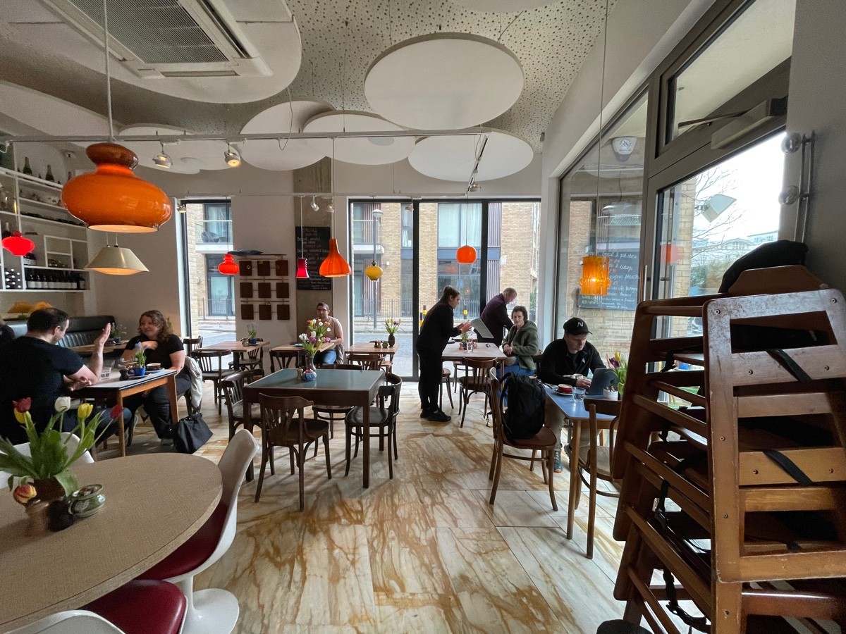 From entrance facing right. High baby chairs on right. Tables and chairs behind, along back and left. Half booth on back left.