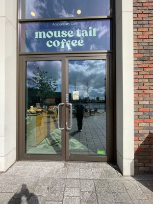 Facing glass doors with brown frame. Push sliver handle in center to open.