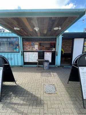 From street, facing venue. A-frame board on both sides. Counter along back. Doorway at back right.