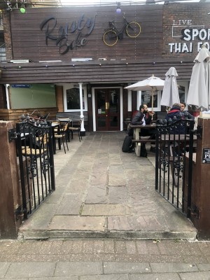 Step up before black gates. Push gates from centre to open. Path ahead to entrance doors at back.