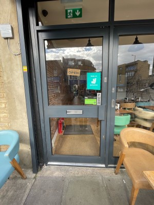 Glass door with grey frame. Push handle on right to open.