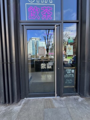 Glass door with grey metal frame ahead. Push from metal handle on right to open.