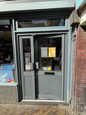 Glass door with grey frame. Push from left to open.