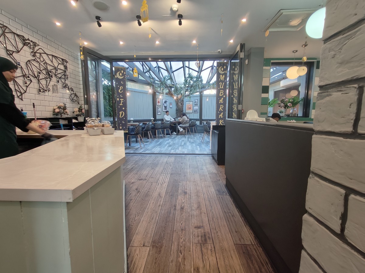 From end of counter facing straight. Condiment station on left. Path ahead to back area. Partition on right.