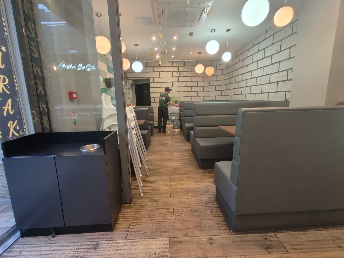 From end of condiment station facing right. Booths along right. Glass partition and bin on left. Booths behind.