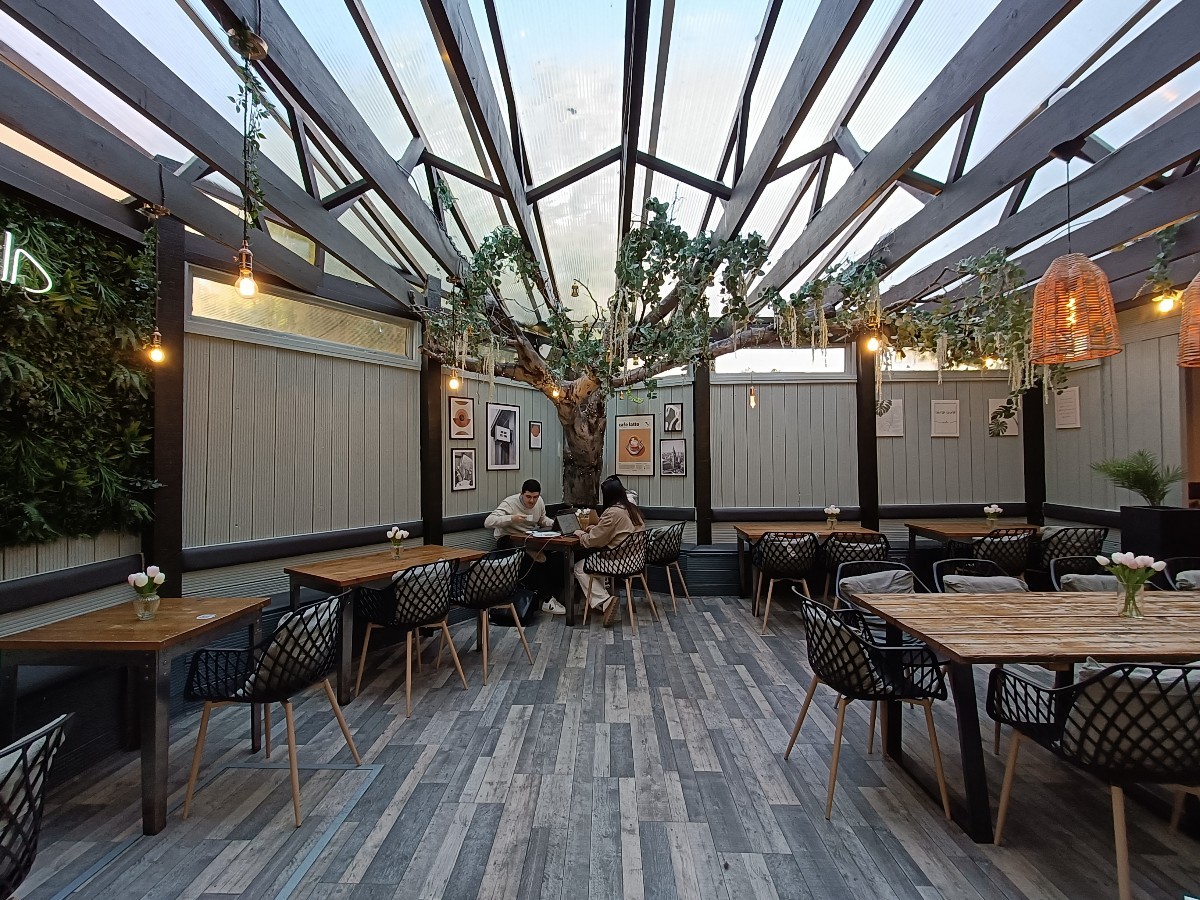 From doorway, looking straight. Half-booths and chairs along left and back. Tables and chairs along right.