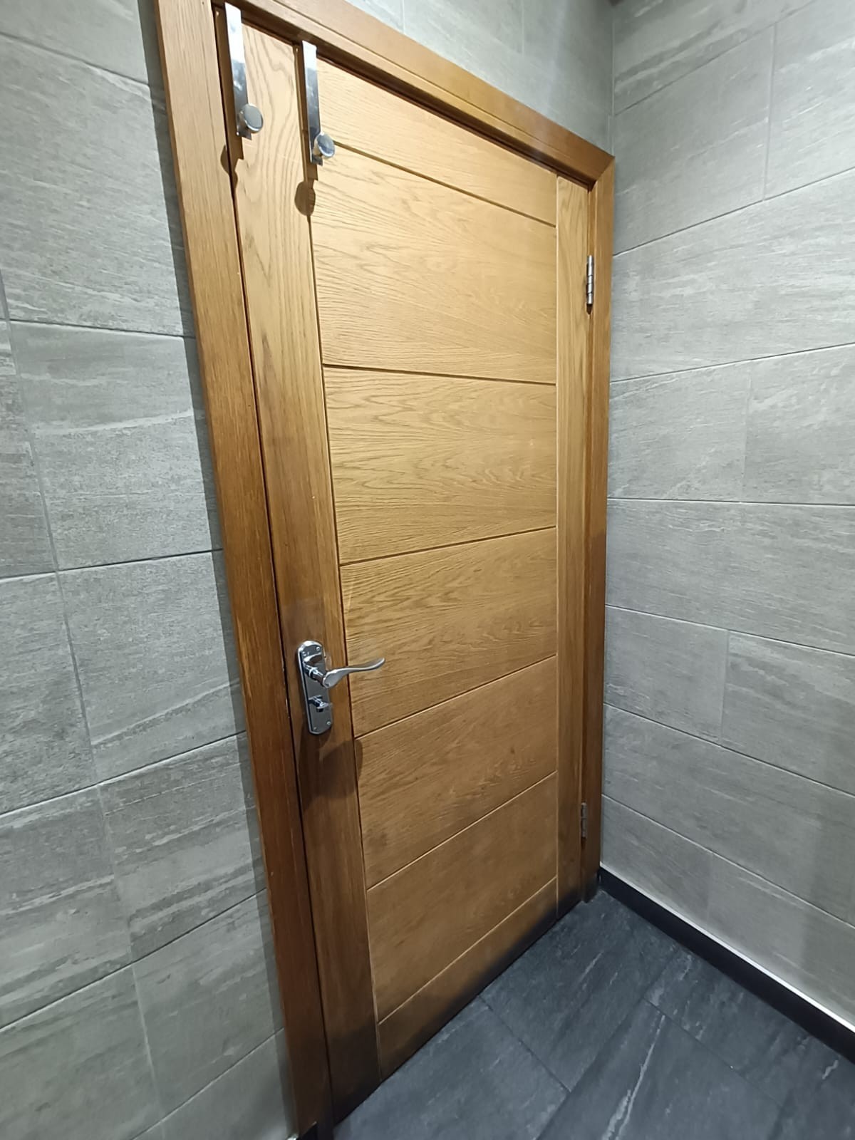 Back of door. High hooks at top left. Pull silver handle on left to open.