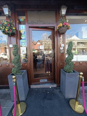From street facing venue. Glass door with brown frame ahead. Push golden handle on right to open.