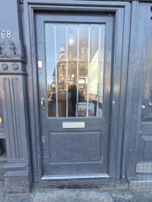 Grey framed glass door. Push golden handle on left to open.