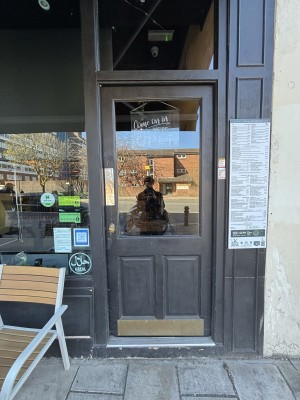 Glass door with black frame. Push from left to open.