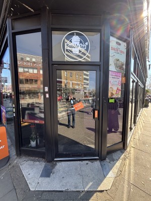 Glass door with black frame. Push from right to open.
