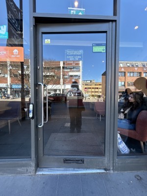 Glass door ahead with grey frame. Silver handle on left. Push to open.