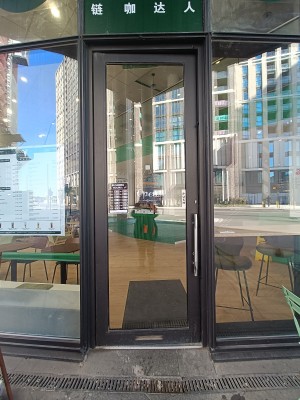 Glass door with black, metal frame. Push silver handle on right to open.